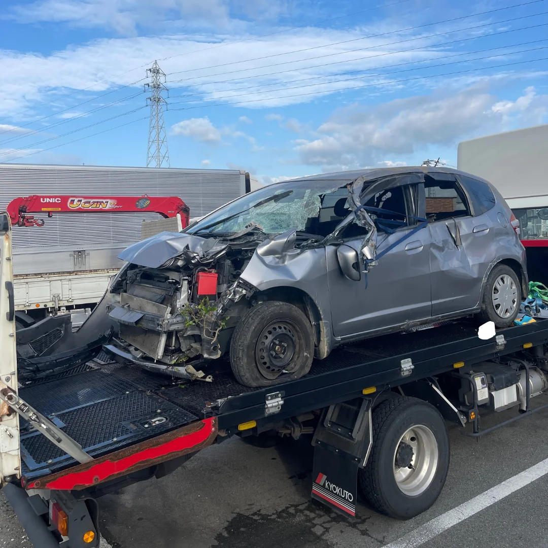 農業用トラクターとの事故で大破したホンダフィットをクレーン付き車両で引き離し、一時保管を経て整備工場へ搬送する様子