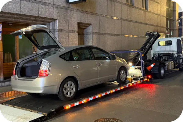 夜間、福岡市内の路上で故障車をレッカー車に積載している様子