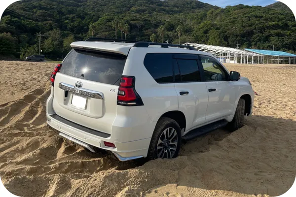 白のSUVが砂浜でスタックしている状態（海辺の救出シーン）