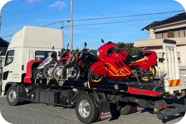 積載トラックに複数のバイクを並べて固定し輸送している様子（晴天）